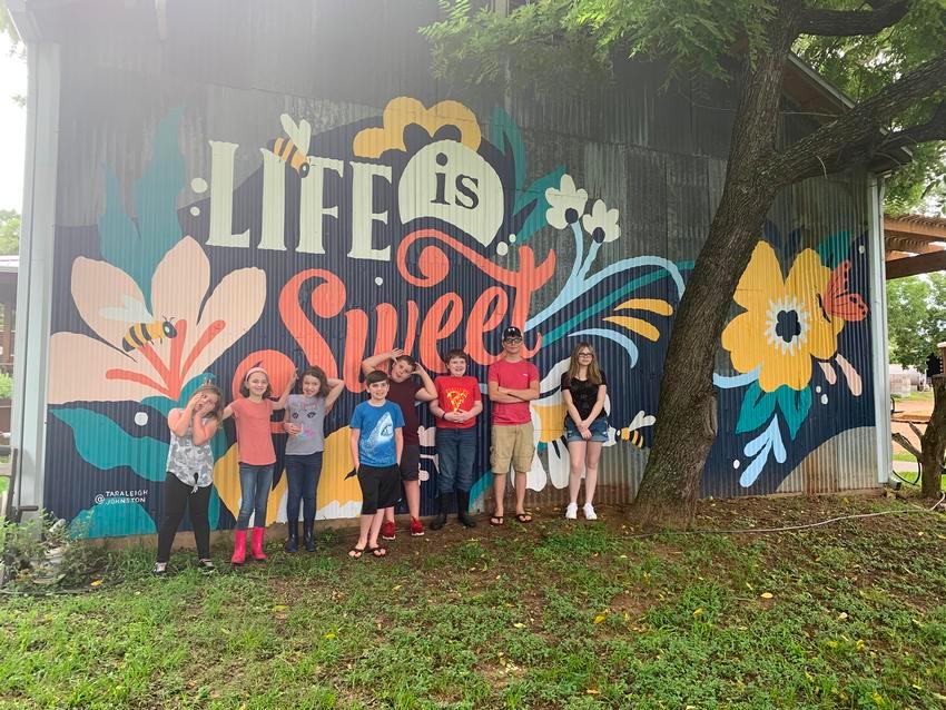 A group of people standing in front of a mural.